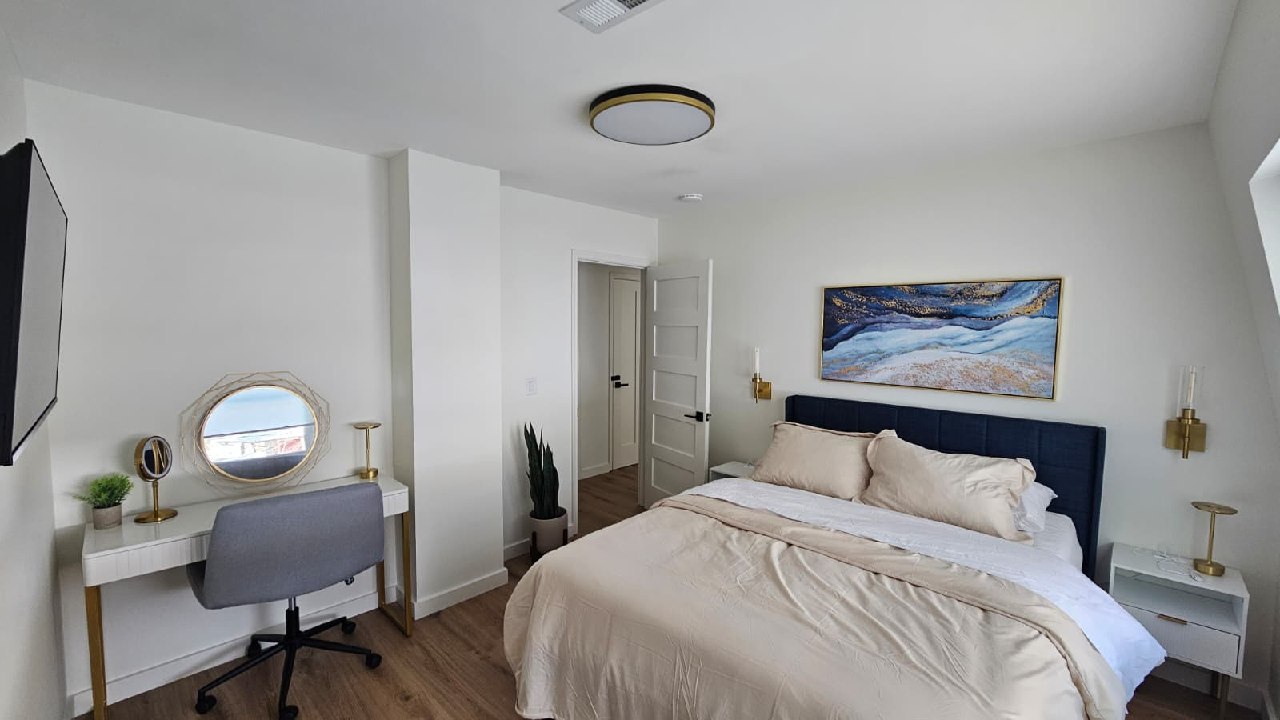 The Gatsby Room with vanity desk, gold sconces, and blue abstract art